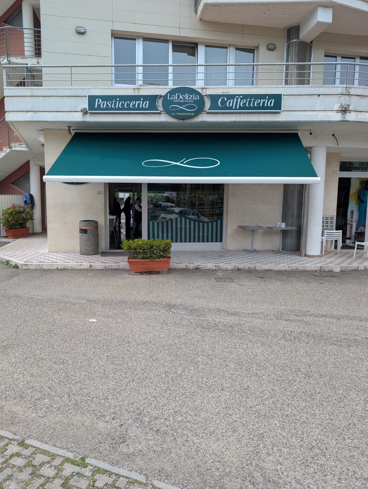 Un piccolo negozio con una tenda da sole verde e un'insegna con la scritta