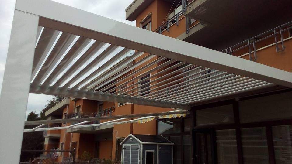 Moderno condominio con una tettoia a lamelle bianche sopra un passaggio pedonale esterno e l'ingresso.