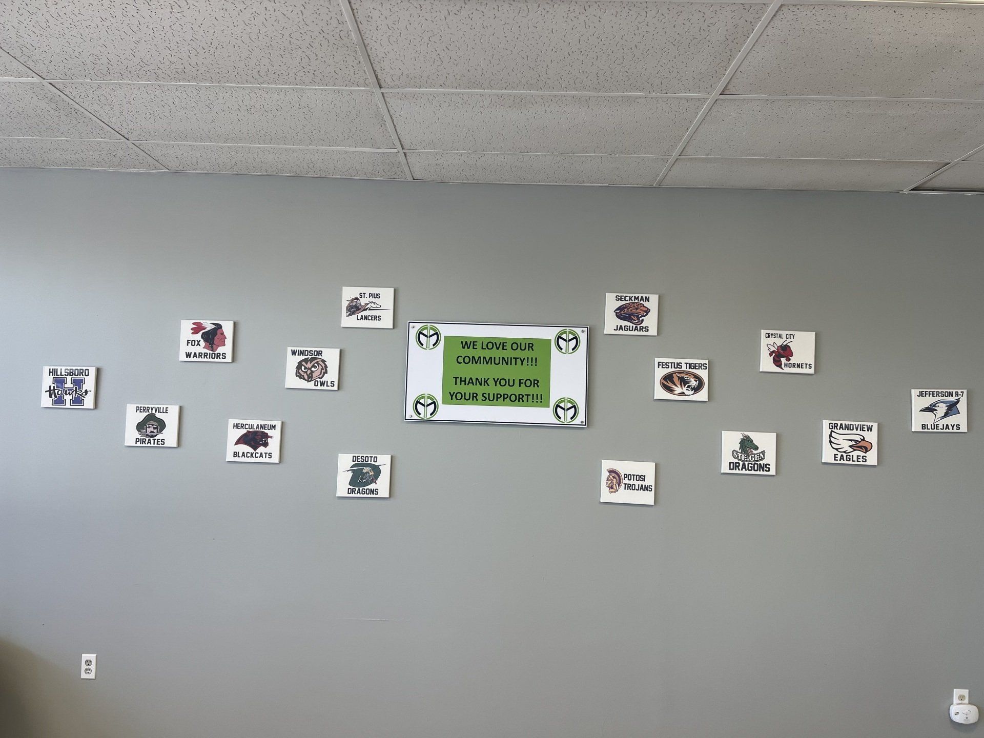 Gray wall with a row of small photos and a green sign centered on it.