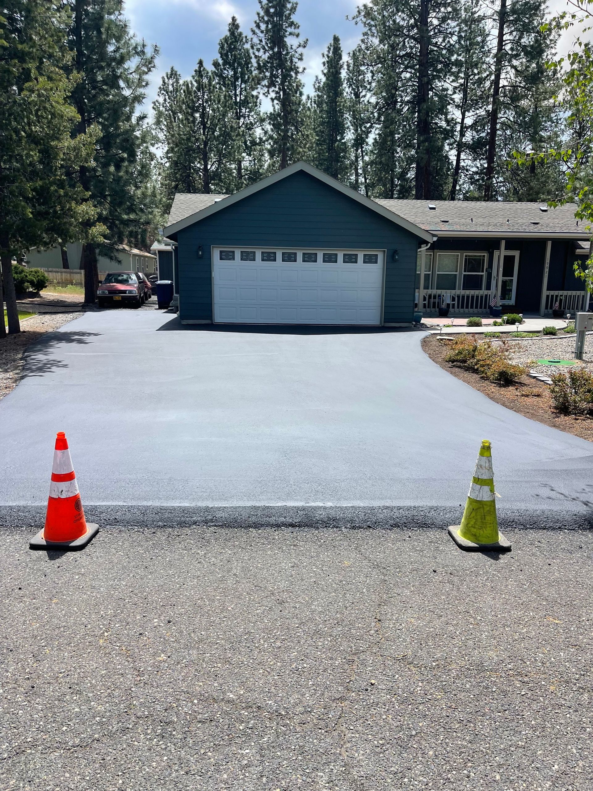 A driveway with two traffic cones in front of a house.