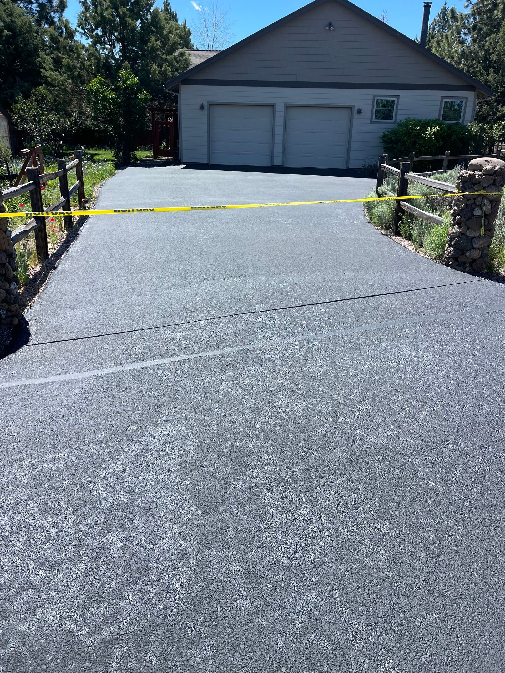 A driveway with a yellow tape on it and a house in the background