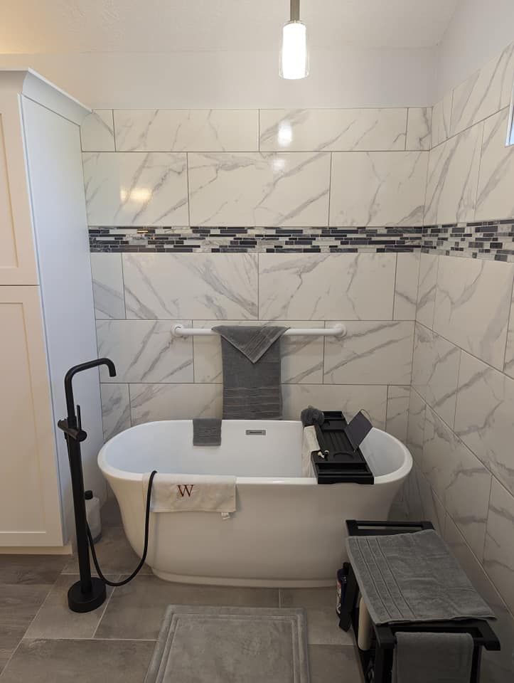 Bathroom with a white oval bathtub, black faucet, and marble-patterned tile.