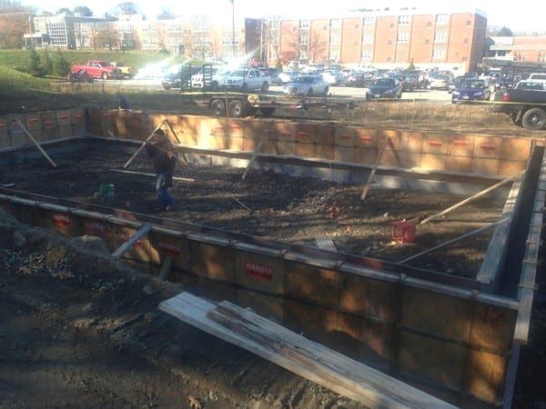 A large concrete wall is being built on a construction site.
