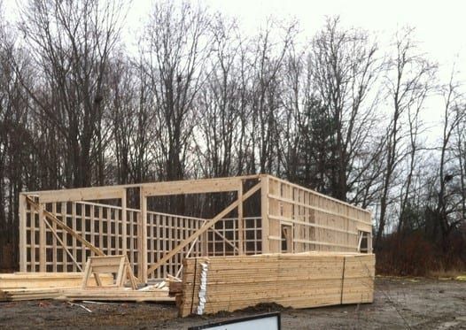 A large wooden structure is being built in the middle of a forest.