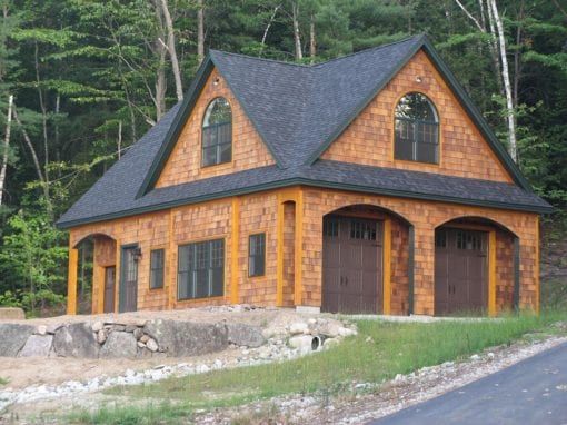 A large house with a black roof is surrounded by trees