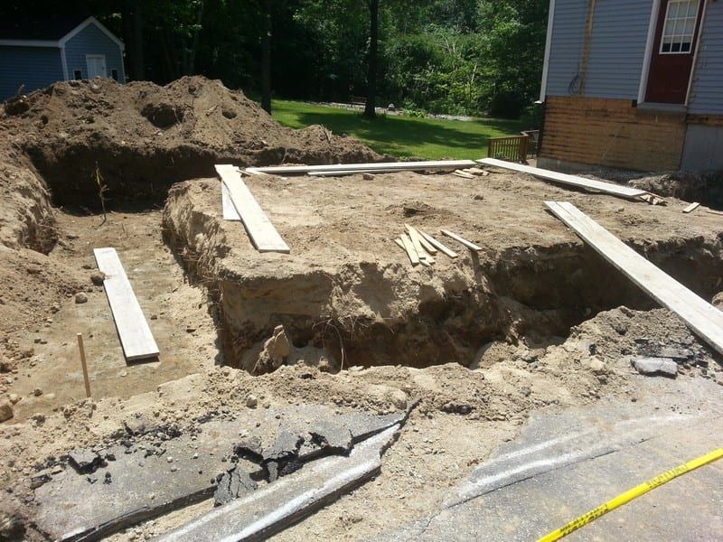 A large pile of dirt with a house in the background