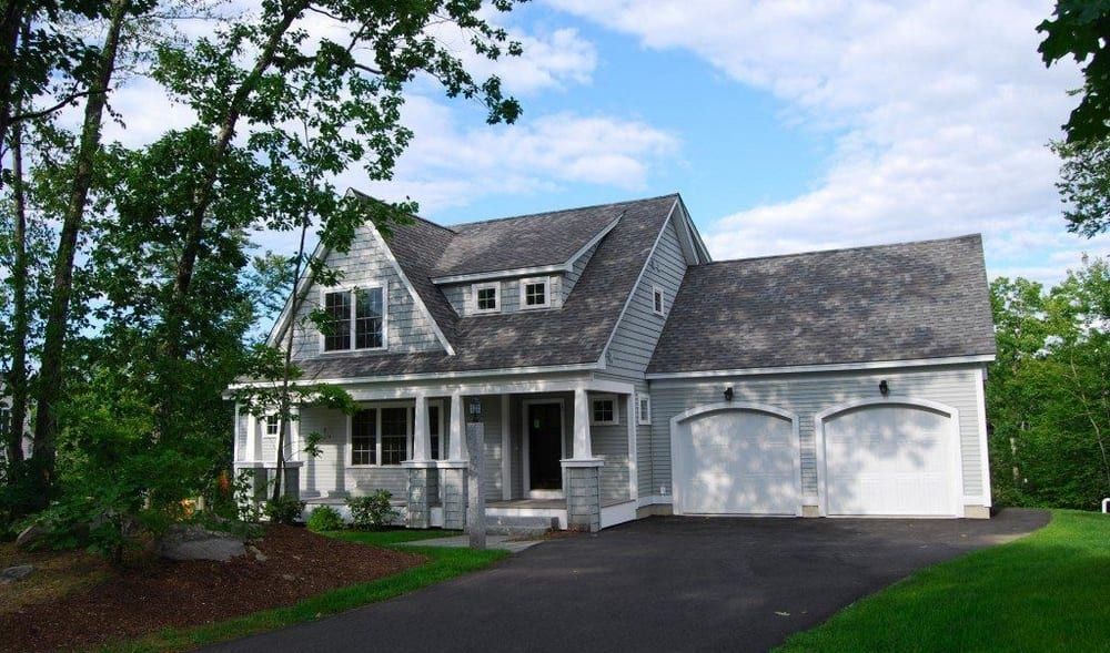 A white house with a gray roof and two garages