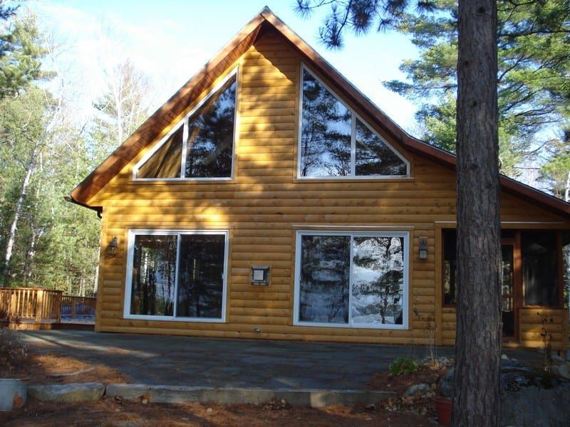 A log cabin with a triangle roof and lots of windows