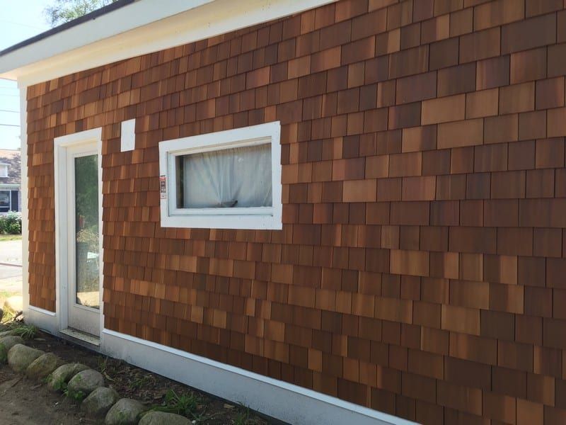 A brown house with a white trim and a window on the side.