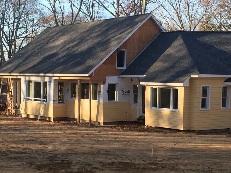 A yellow house with a black roof is under construction
