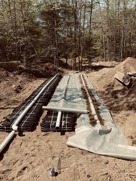 A septic system is being built in the dirt in the woods.