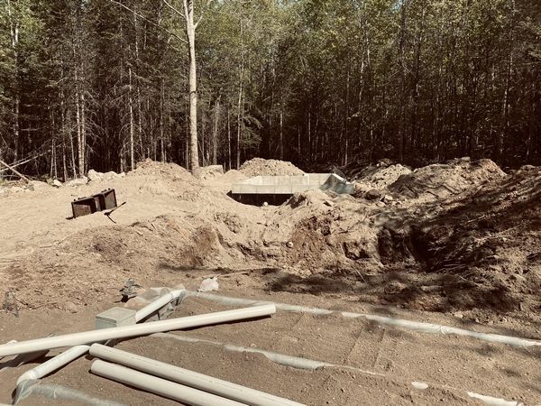 A pile of dirt and pipes in the middle of a forest.