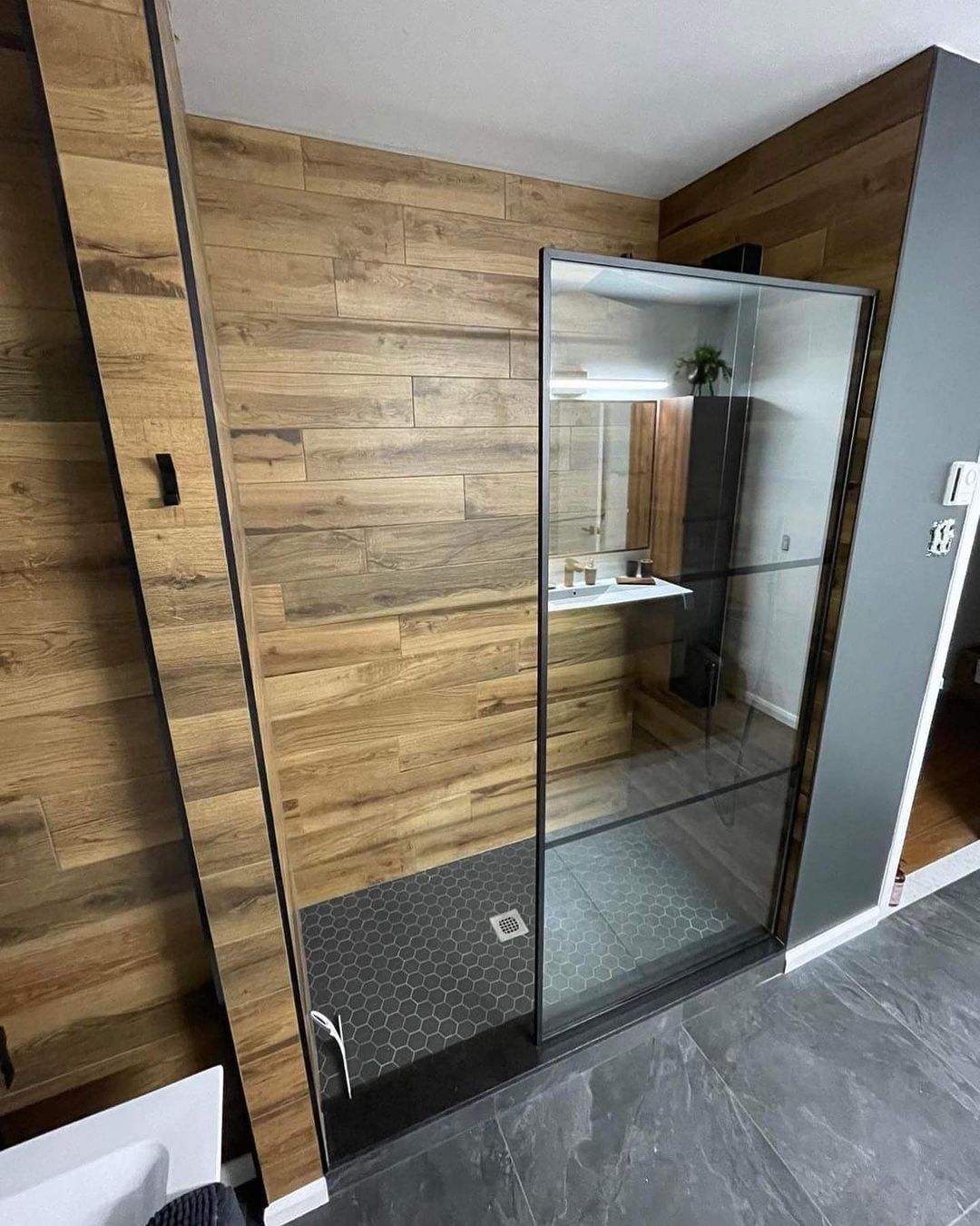 Une salle de bain avec douche à l'italienne et un mur en bois.