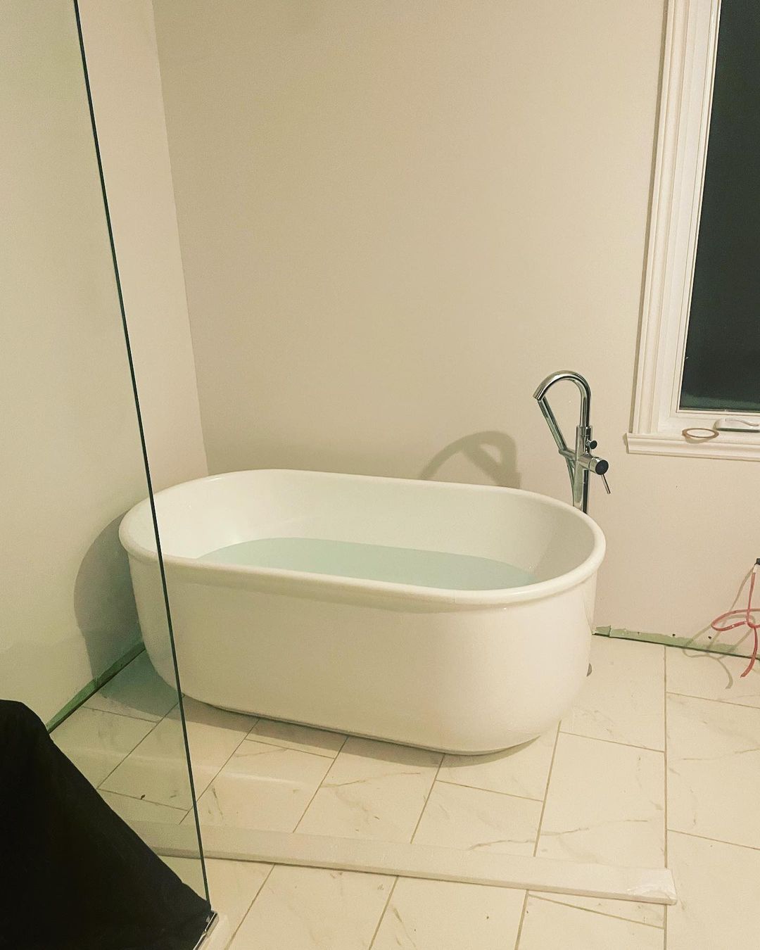 Une baignoire dans une salle de bain à côté d'une fenêtre