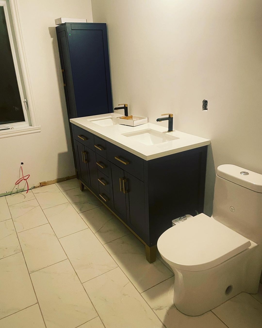 Une salle de bain avec deux lavabos, un WC et une fenêtre.