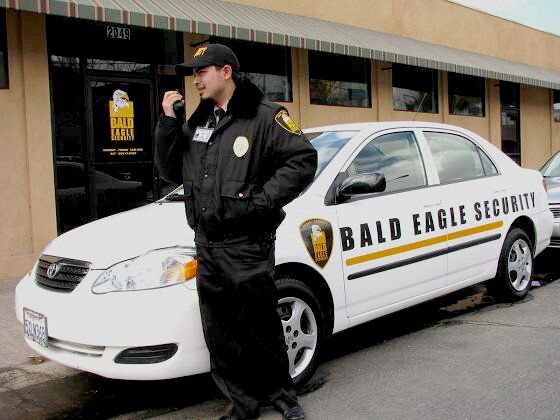 San Diego security guard on walkie-talkie in front of patrol vehicle