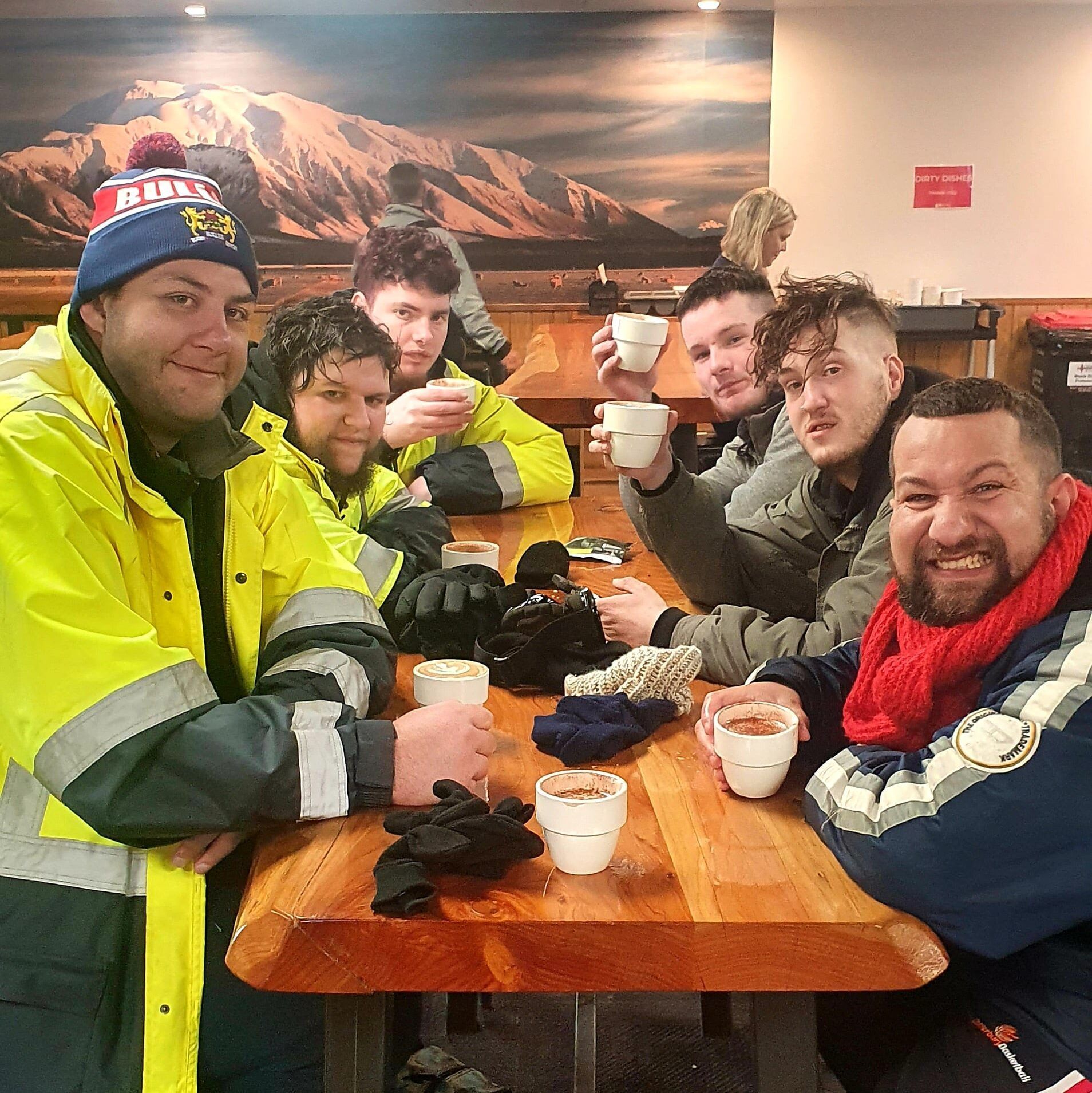 A group of men are sitting at a table drinking coffee