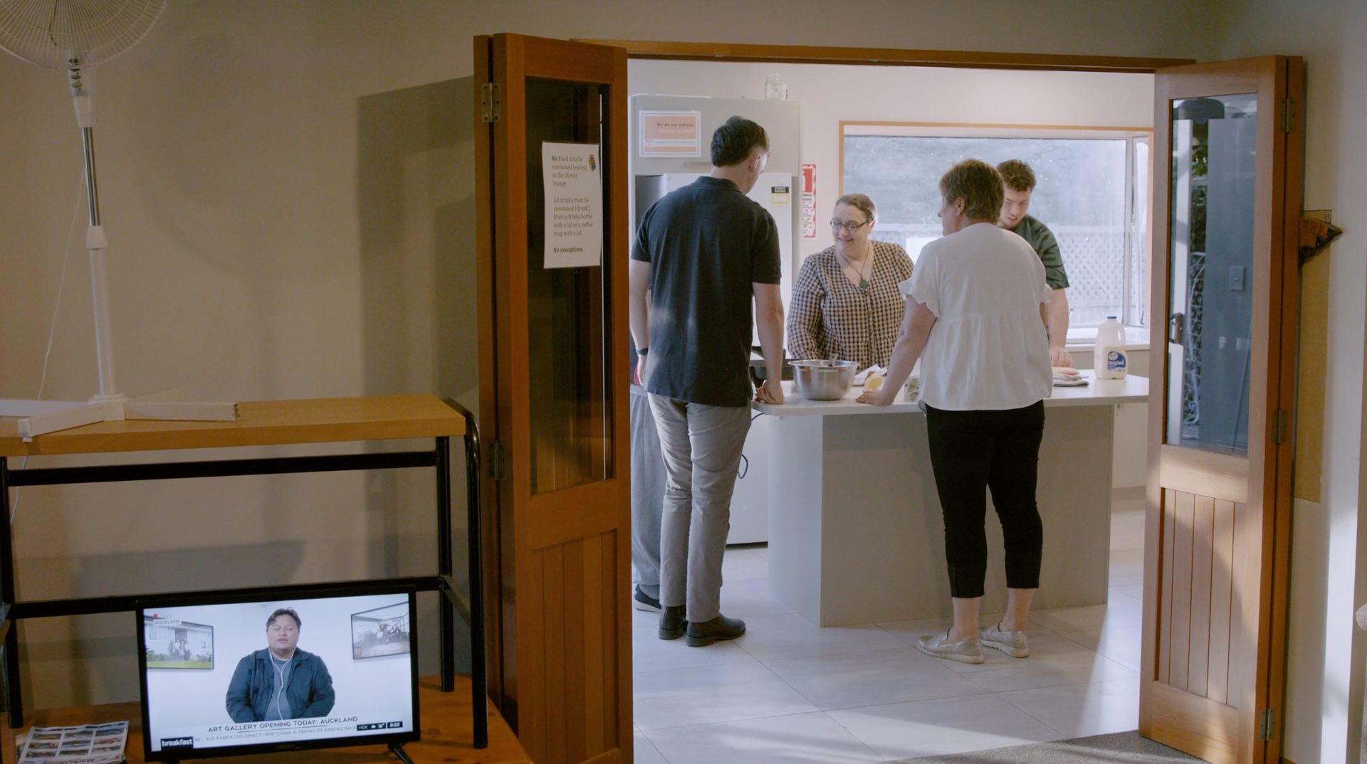 A group of people are standing in a room talking to each other.