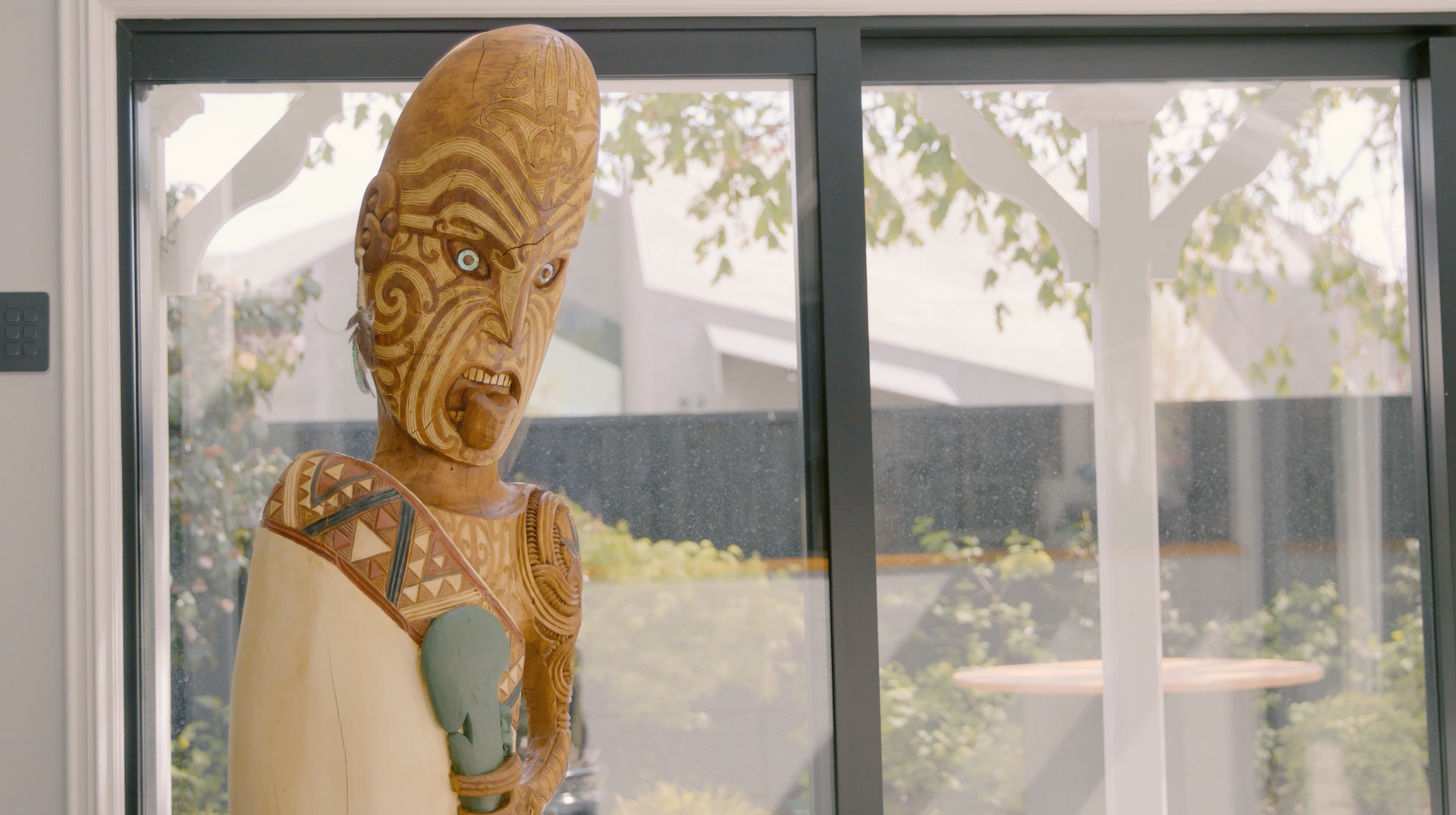 A statue of a man is standing in front of a sliding glass door.