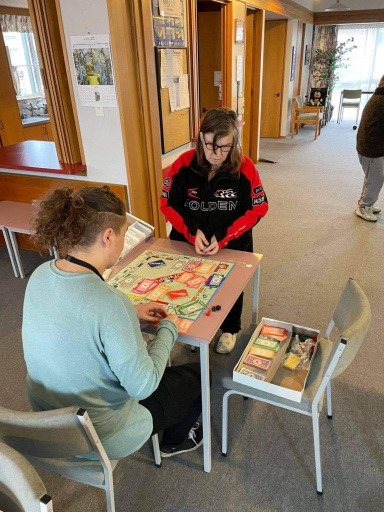 Two people are sitting at a table playing a board game.