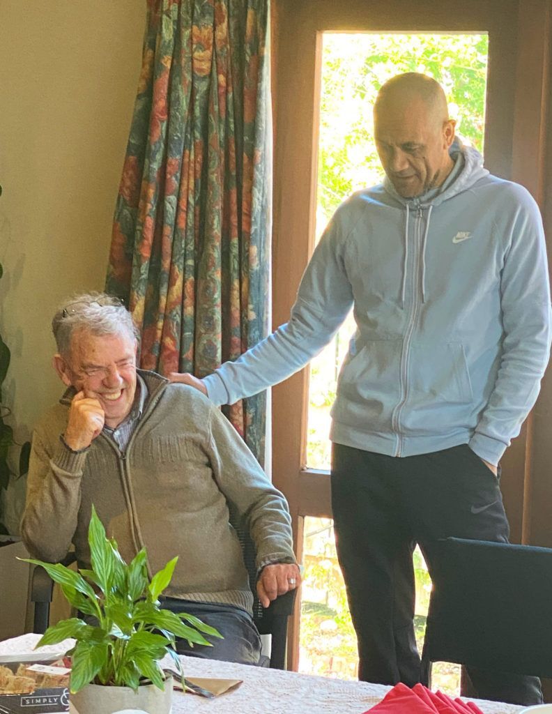 Two men are standing next to each other in a living room.