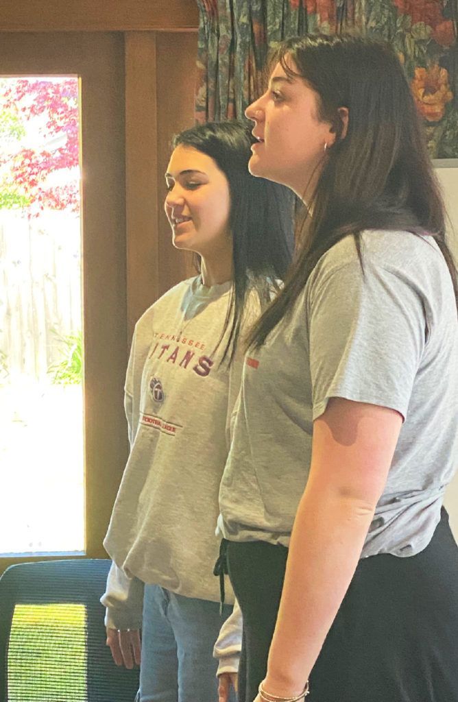 Two young women are singing together in a room.