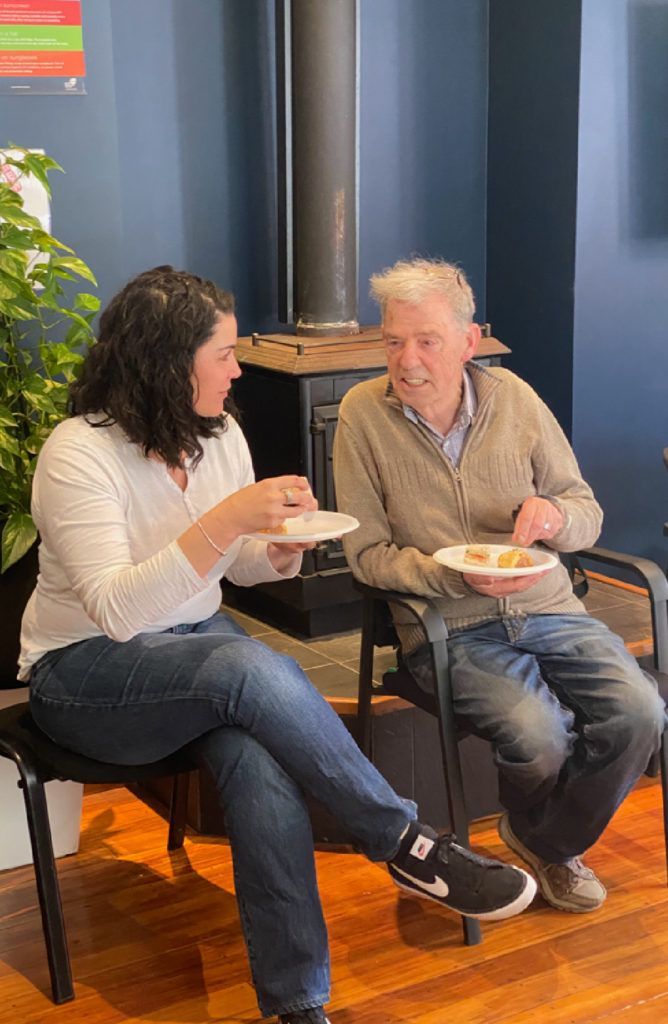 A man and a woman are sitting in chairs eating food.