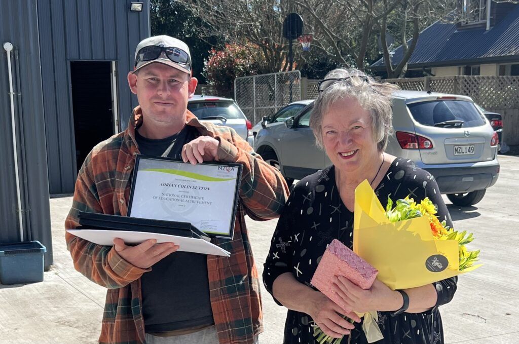 A man is holding a certificate and a woman is holding a bouquet of flowers.
