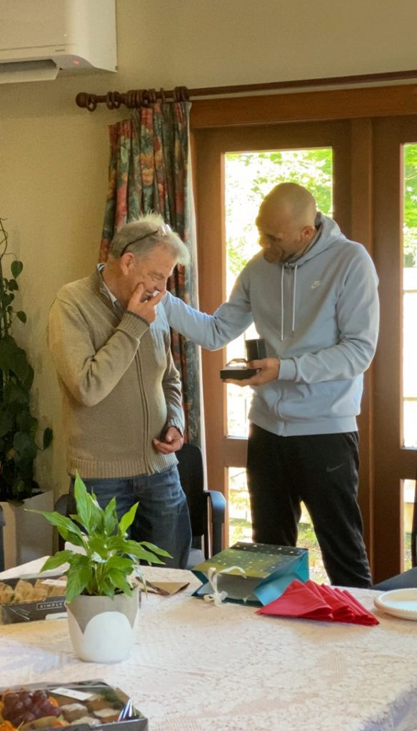 Two men are standing next to each other at a table in a living room.