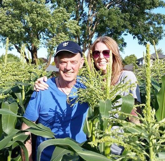 A man and a woman are posing for a picture in a corn field