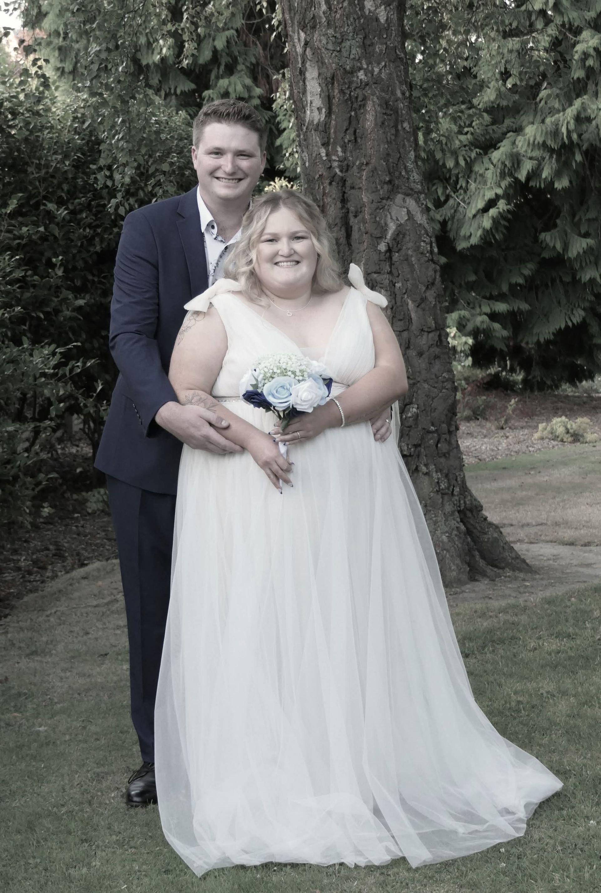 A man is holding a certificate and a woman is holding a bouquet of flowers.