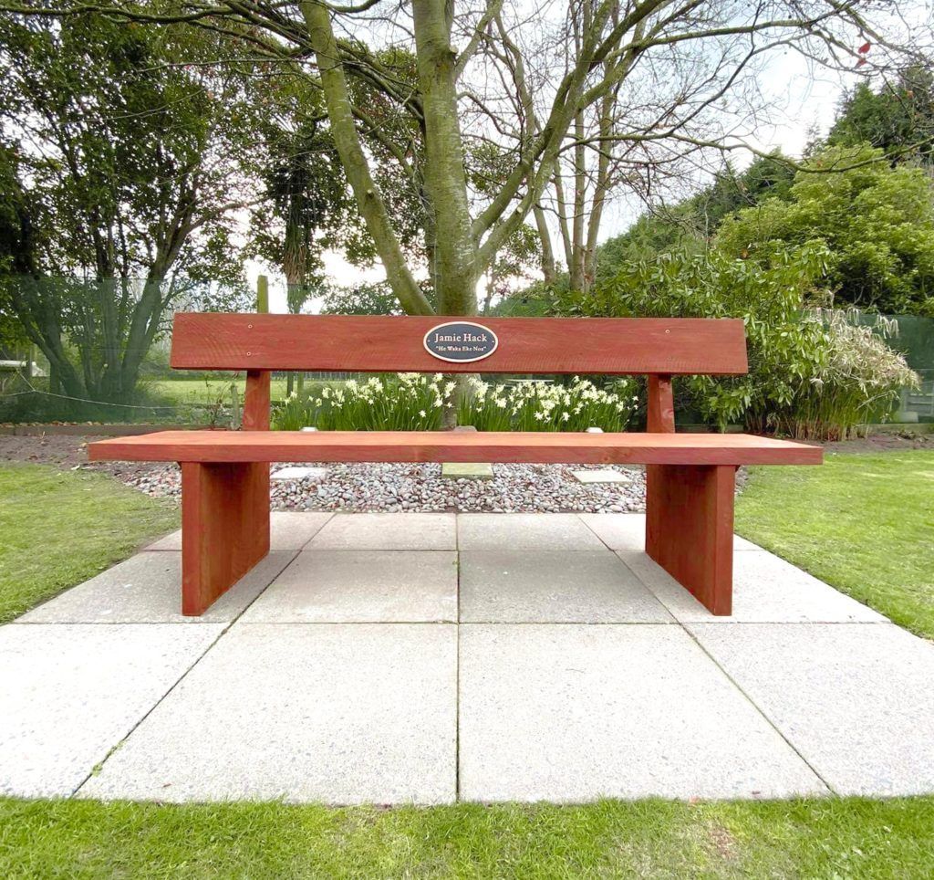 A wooden bench in a park with a plaque on it