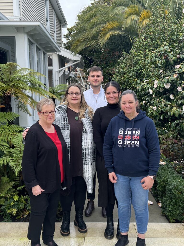 A group of people are posing for a picture in front of a house.