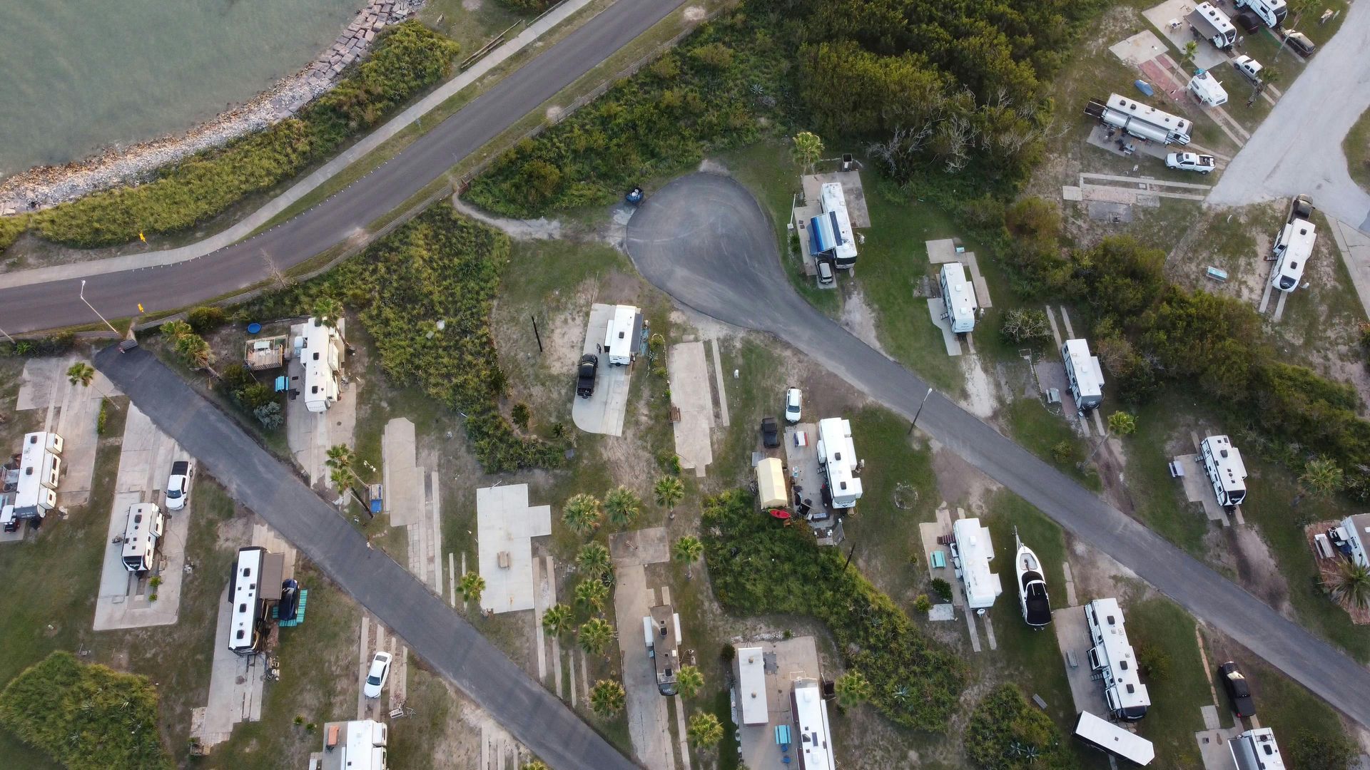 Aerial view of an RV campground with parked trailers, winding roads, and trees.