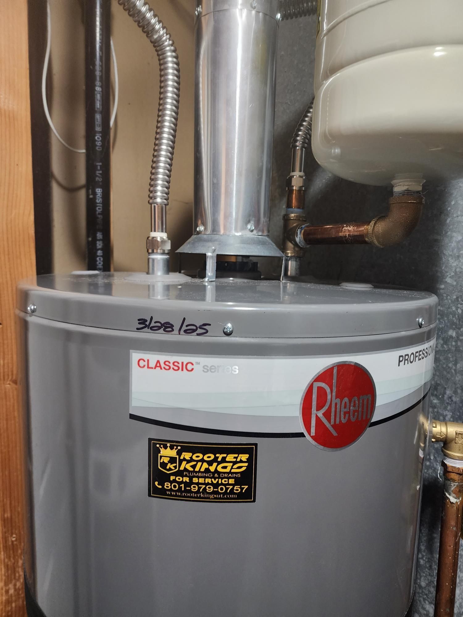 Gray Rheem water heater in a utility closet with a flue and piping.
