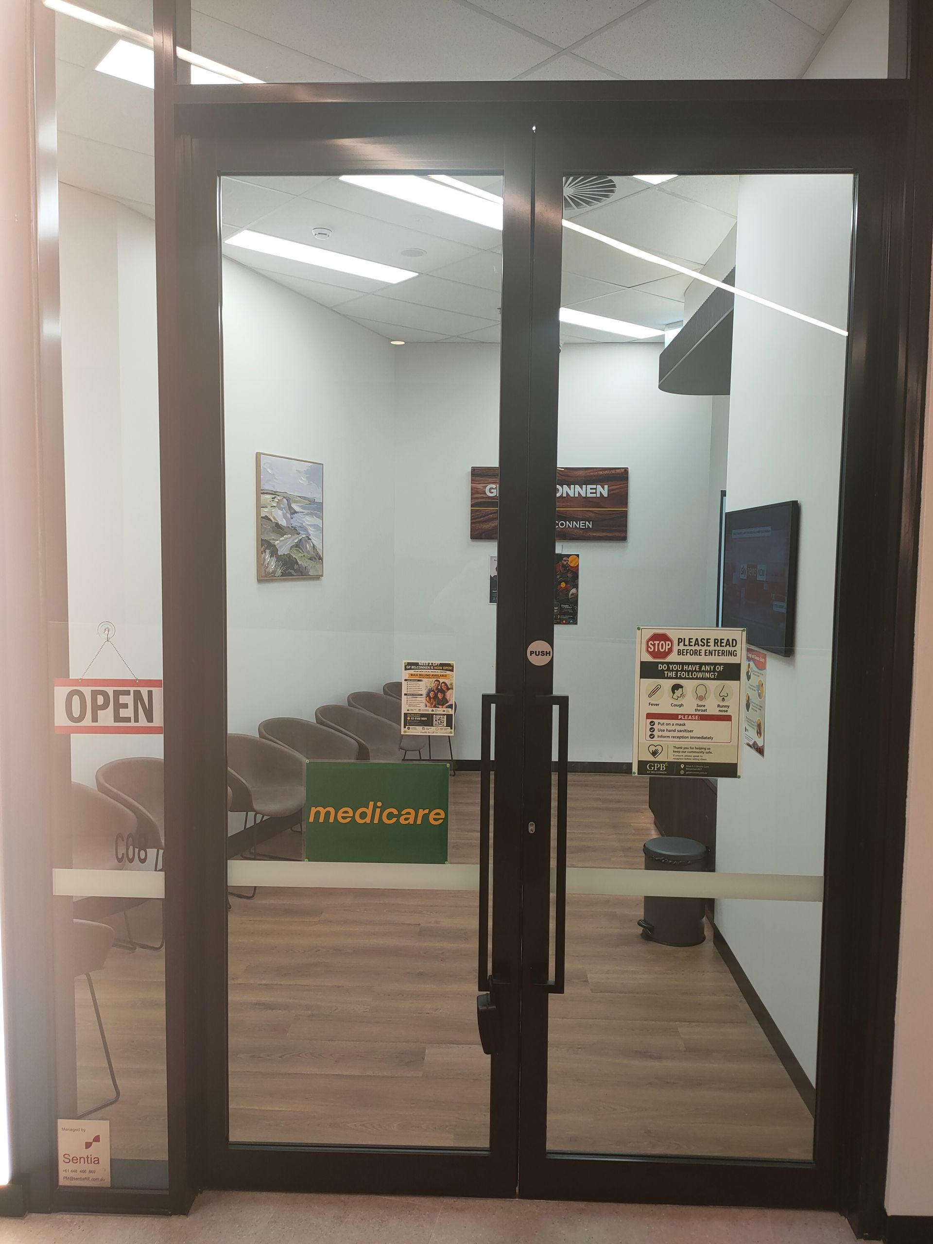 GP Belconnen medical centre entrance doors showing the waiting area, Medicare sign and patient information posters.