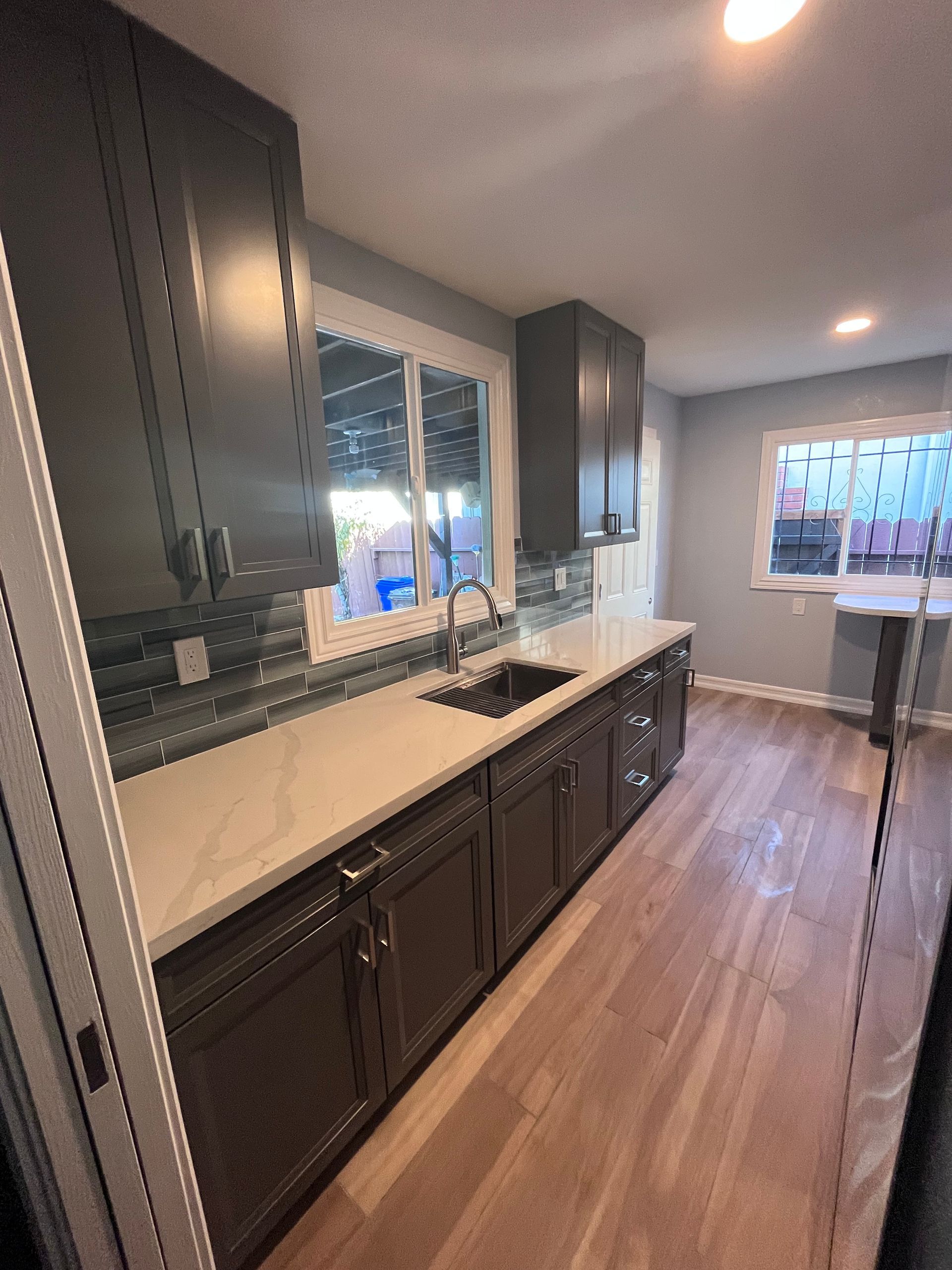 Dark wood kitchen cabinets with white countertop, sink, and window.