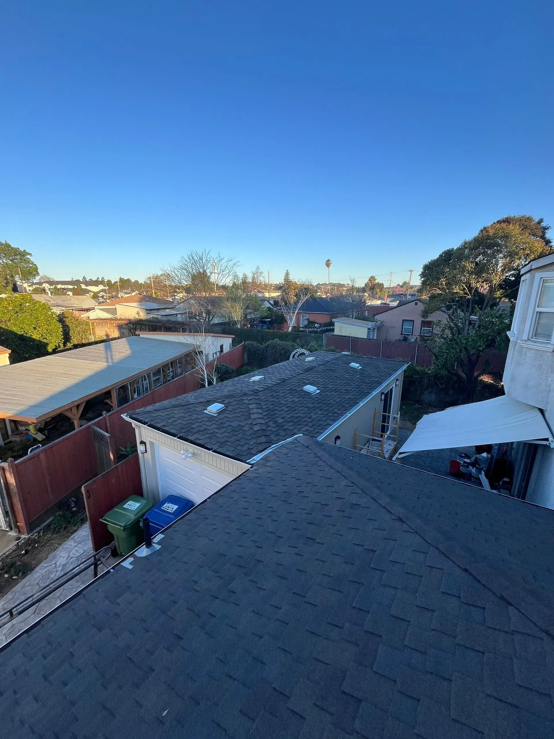 View from a rooftop, looking over other houses and a clear blue sky.