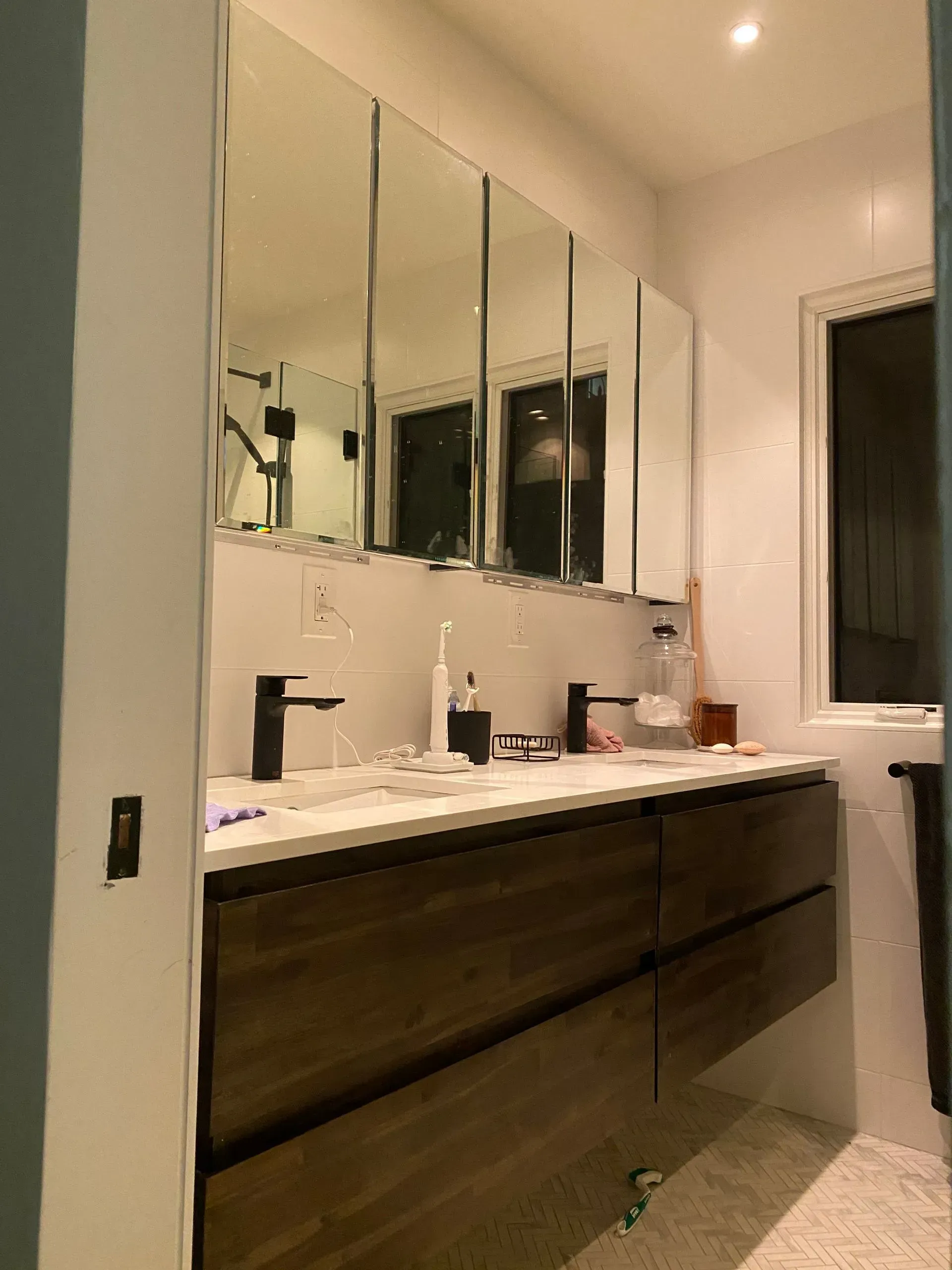 Modern bathroom with a dark wood vanity, double sinks, and mirrored medicine cabinets.