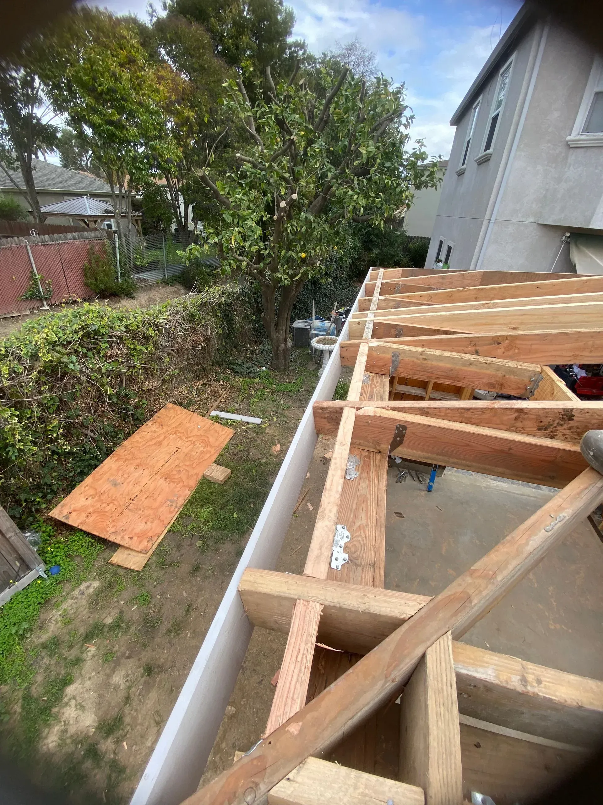 Construction of a wooden roof frame; building materials and greenery.