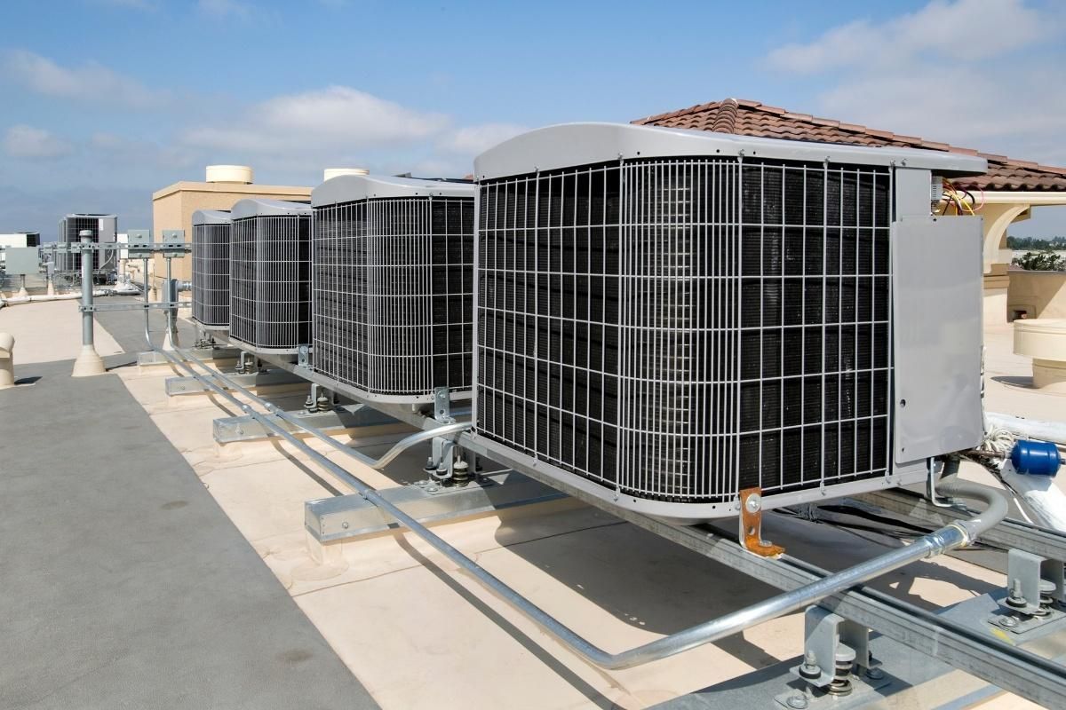 Row of rooftop air conditioning units on a sunny industrial building roof