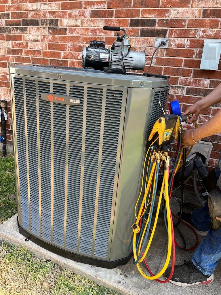 Outdoor HVAC unit with gauges and hoses attached against a brick wall