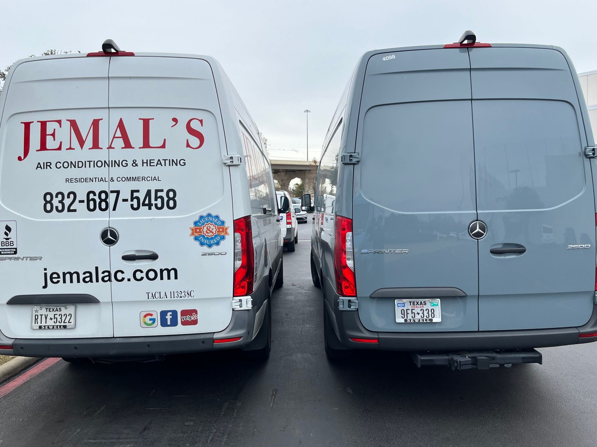 Two white delivery vans parked side by side, one branded JEMAL’S with contact info.