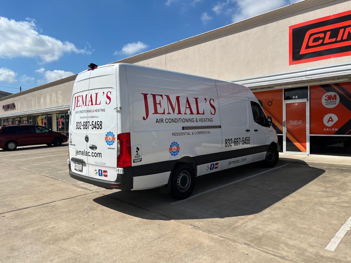 White JEMAL’S service van parked outside a commercial building on a sunny day