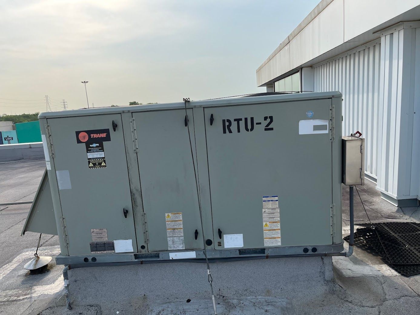 Gray RTU-2 HVAC unit beside a white building on a paved lot.