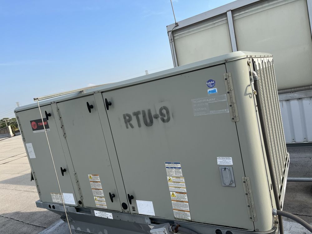 Large beige rooftop HVAC unit on a building roof under a clear blue sky.