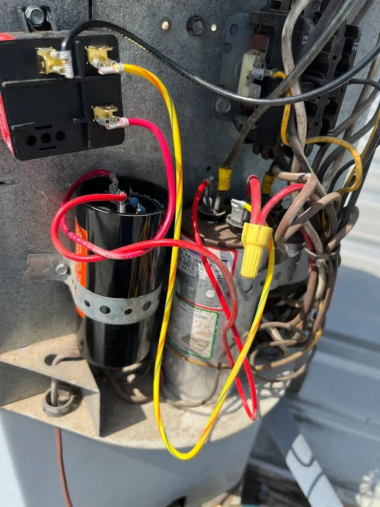 Close-up of electrical wiring and components inside a metal panel, with red, yellow, and black wires.