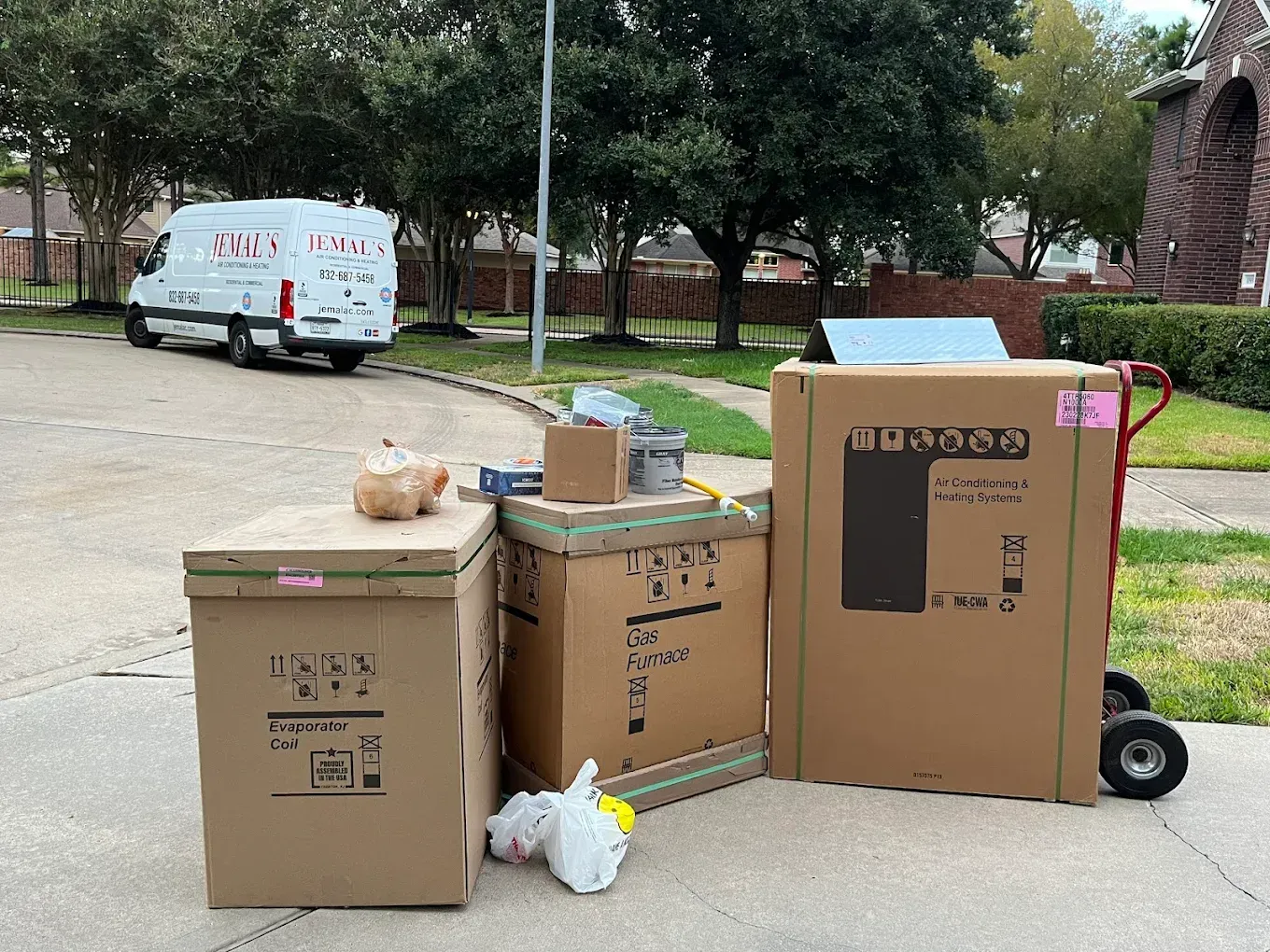 Boxes and bags of donations stacked on a driveway, with a white van and trees in the background.