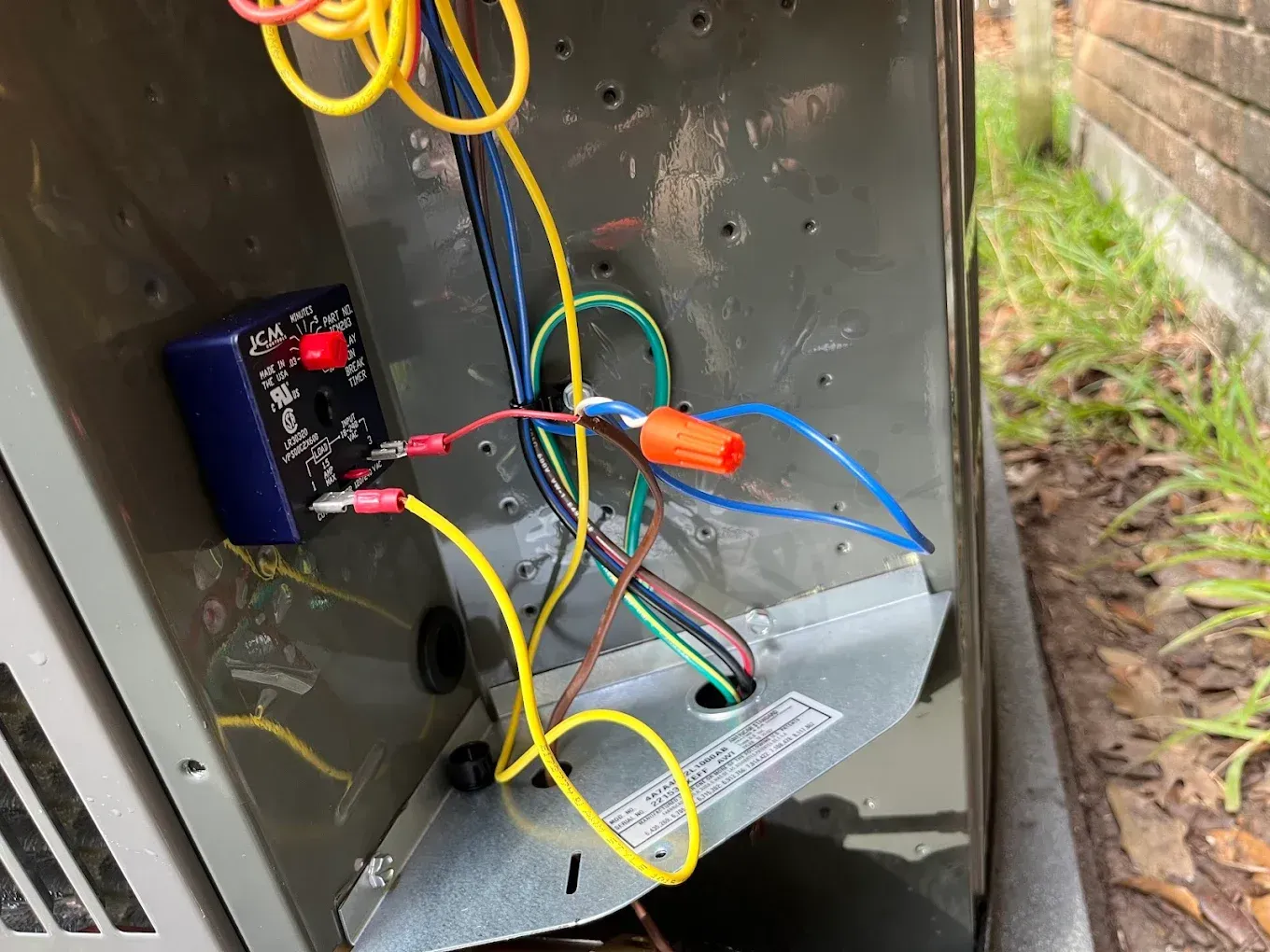Open electrical box with colorful wires and a small black control module mounted inside.