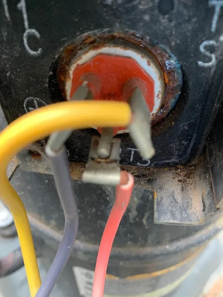 Close-up of a corroded electrical switch with yellow, gray, and red wires attached